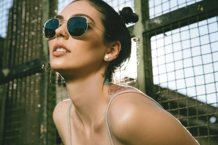 femme souriante sous le soleil avec piercing d'oreille