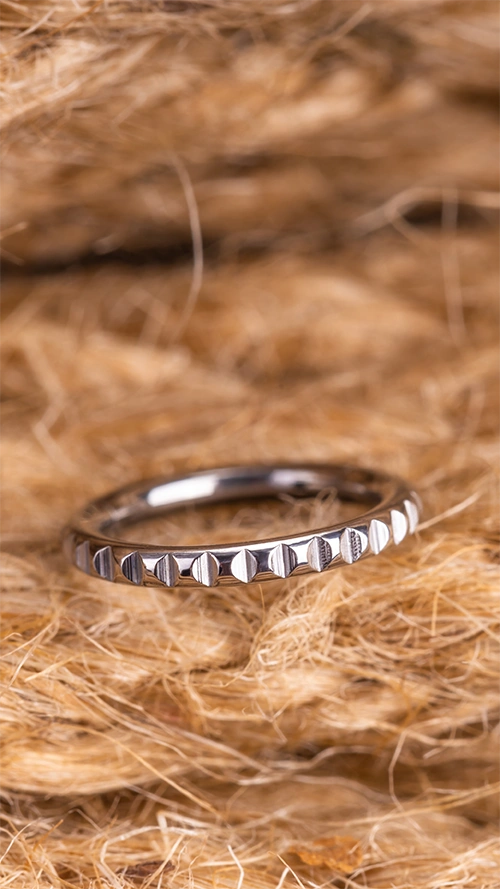 Un piercing en titane argenté posé sur un fond de paille