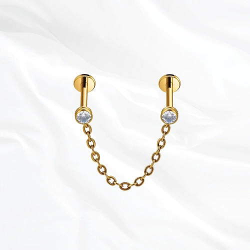Piercing en titane doré Le Maillon, deux labrets sertis chacun d’un zircon et reliés par une chaînette en arc souple