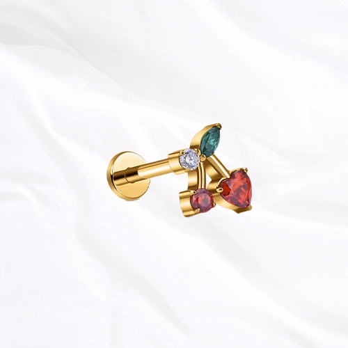 Labret en titane doré La Cerise, deux cerises rouges sur une même branche, l’une taillée en cœur et l’autre ronde, sous une feuille verte