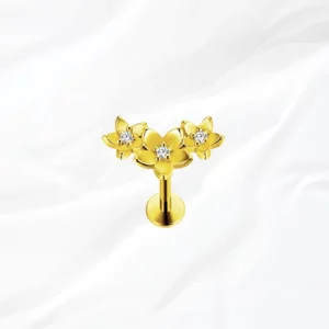 Labret push-in en titane doré La Compo Florale, trois fleurs assemblées en grappe diagonale avec un zircon au cœur de chacune