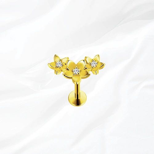 Labret push-in en titane doré La Compo Florale, trois fleurs assemblées en grappe diagonale avec un zircon au cœur de chacune