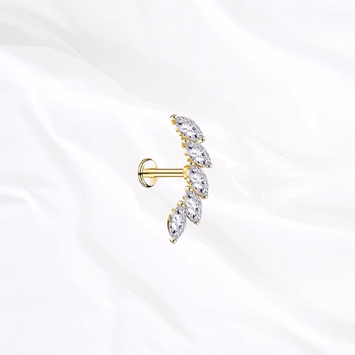 Labret en titane doré La Courbe Royale, cinq zircons marquise sertis sur un arc incurvé qui accompagne l’anatomie de l’oreille