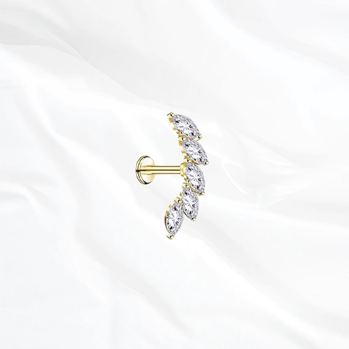 Labret en titane doré La Courbe Royale, cinq zircons marquise sertis sur un arc incurvé qui accompagne l’anatomie de l’oreille