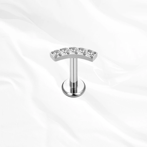 Labret en titane argenté La Parabole, cinq zircons ronds alignés sur une barre légèrement arquée qui suit le relief de l’oreille