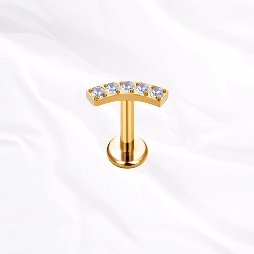 Labret en titane doré La Parabole, cinq zircons ronds alignés sur une barre légèrement arquée qui suit le relief de l’oreille