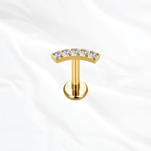 Labret en titane doré La Parabole, cinq zircons ronds alignés sur une barre légèrement arquée qui suit le relief de l’oreille