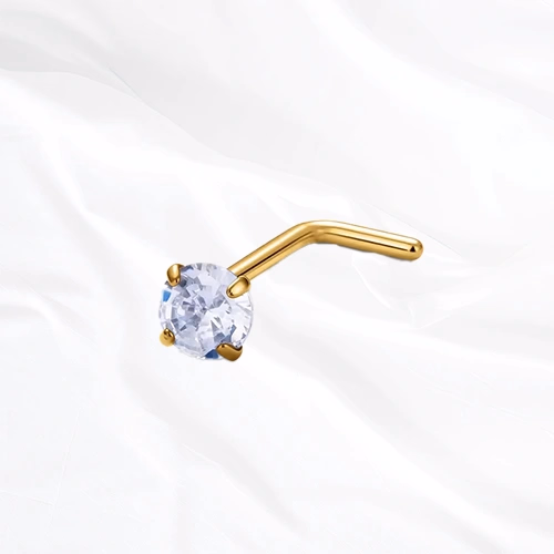 Piercing de nez en titane doré Le Serti, tige coudée en L surmontée d’un zircon tenu par quatre griffes qui le surélèvent