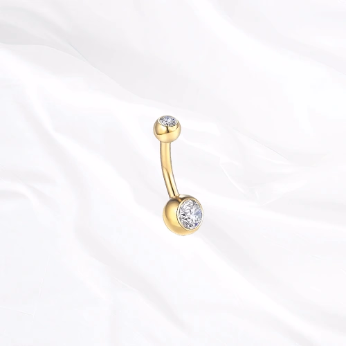 Piercing de nombril banane en titane doré Le Nombriliste, un zircon serti clos à chaque extrémité dans une monture affleurante
