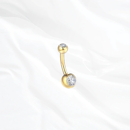 Piercing de nombril banane en titane doré Le Nombriliste, un zircon serti clos à chaque extrémité dans une monture affleurante