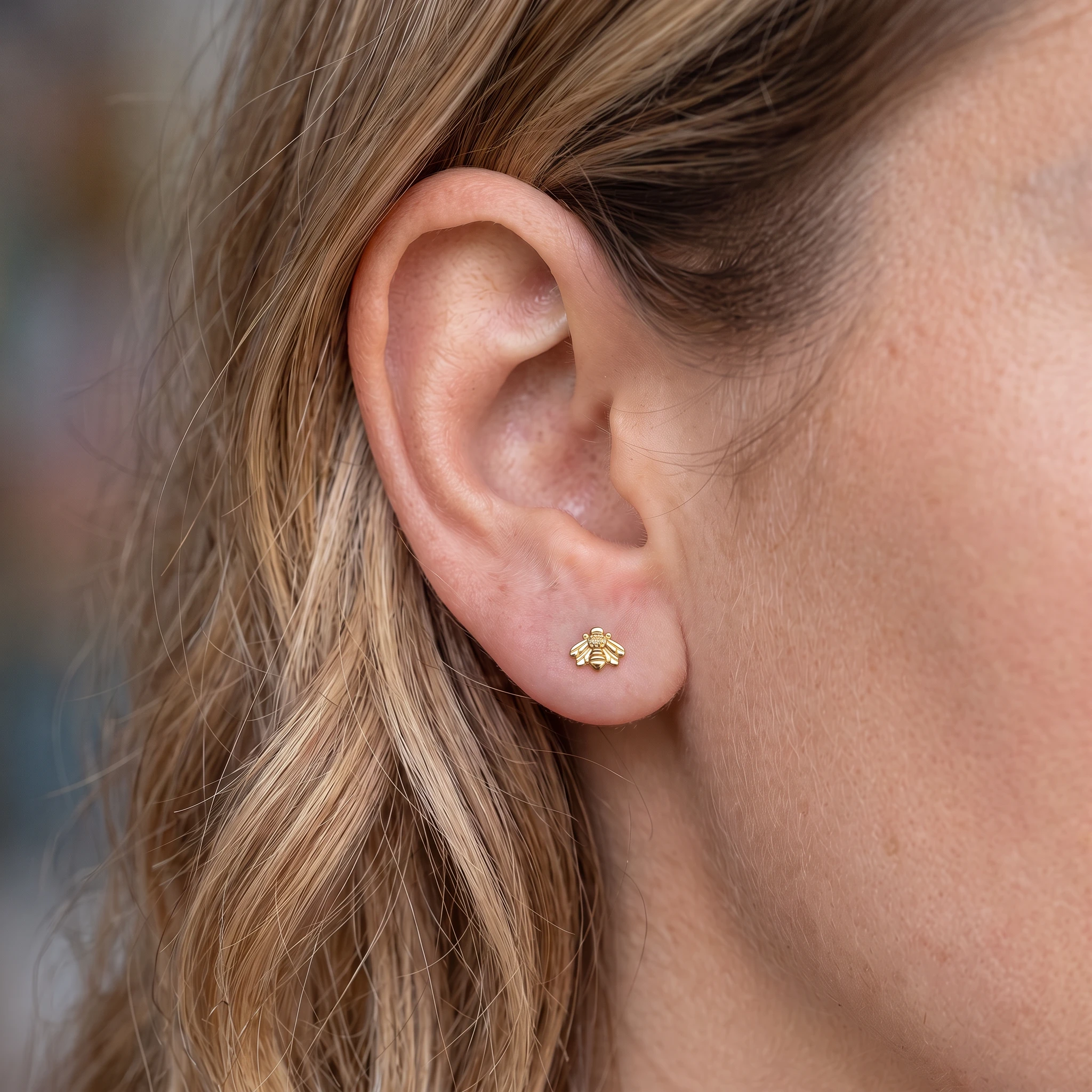 Piercing de lobe en titane doré L'Abeille porté, petite abeille dorée sur le lobe de l'oreille