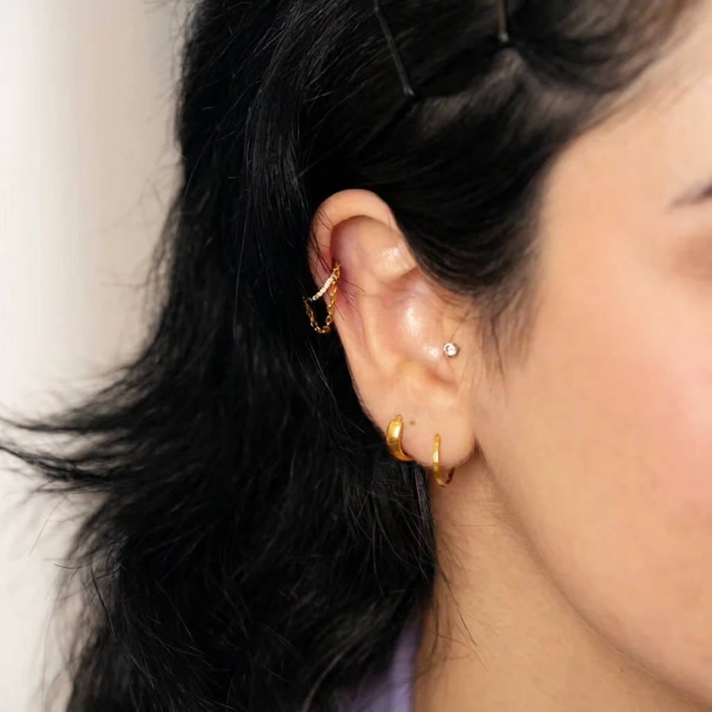 Piercing L'Authentique avec Chaînette en titane doré porté à l'oreille