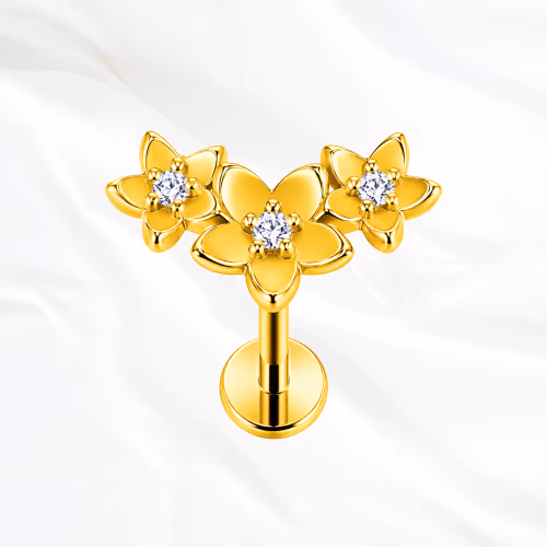 Labret push-in en titane doré La Compo Florale, trois fleurs assemblées en grappe diagonale avec un zircon au cœur de chacune