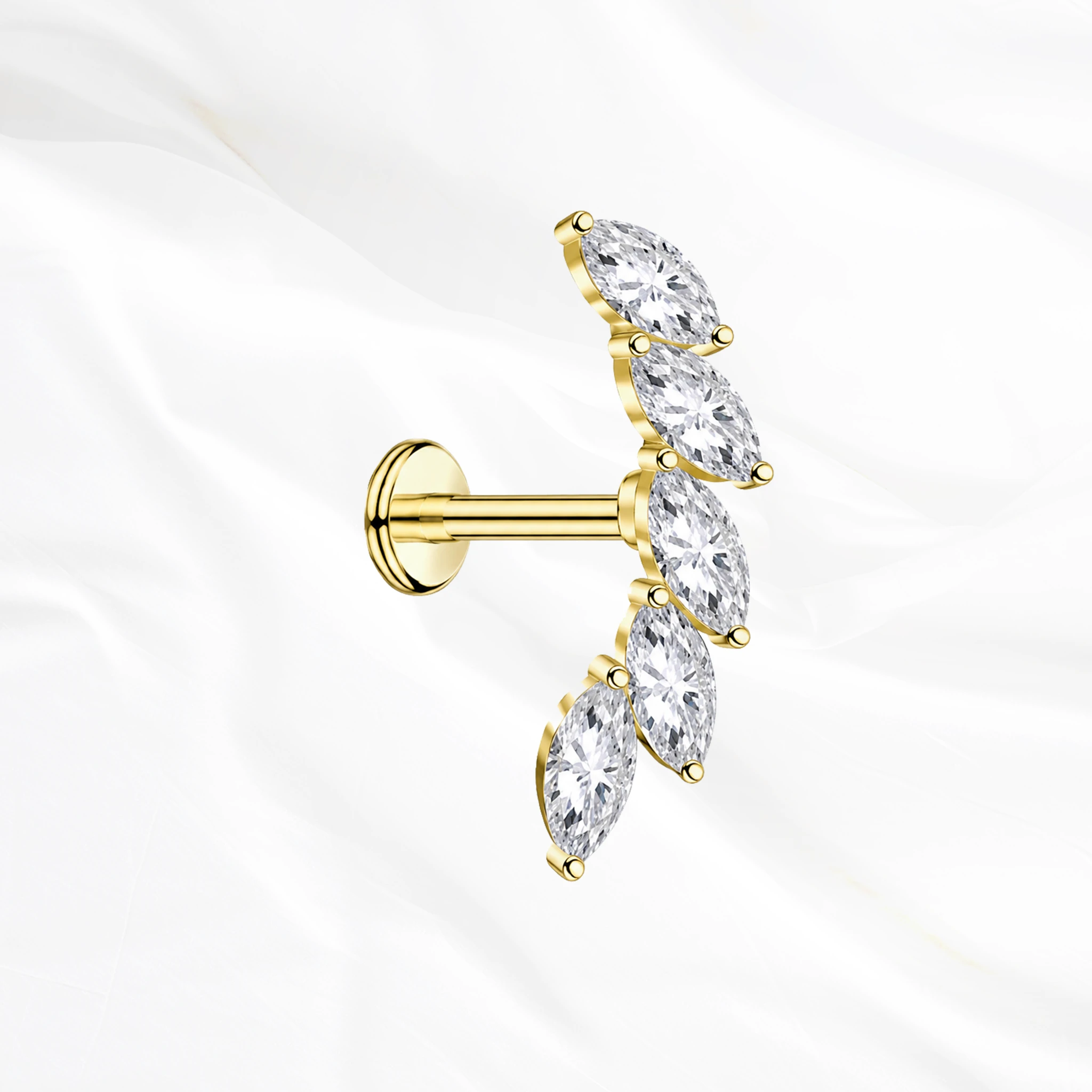 Labret en titane doré La Courbe Royale, cinq zircons marquise sertis sur un arc incurvé qui accompagne l’anatomie de l’oreille