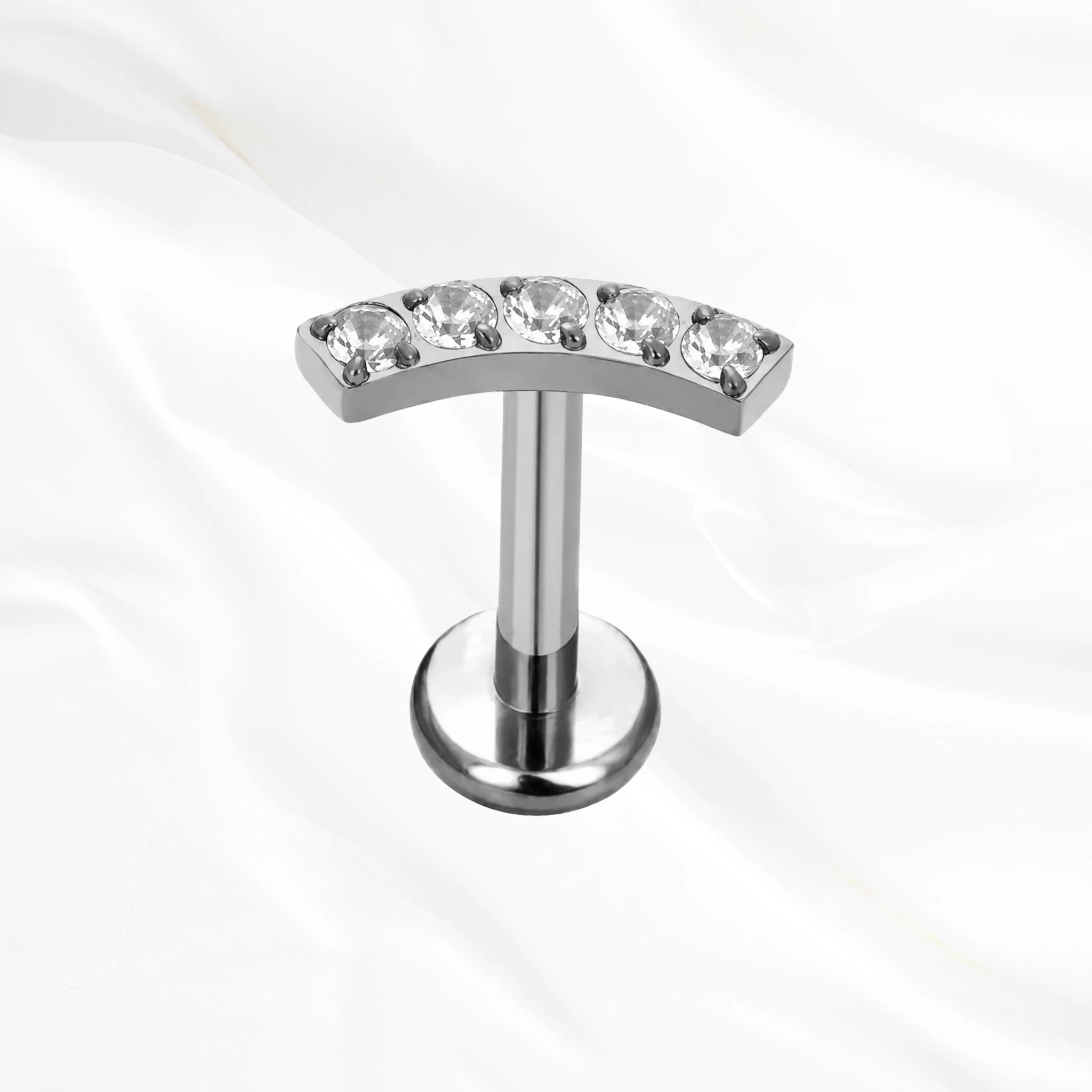 Labret en titane argenté La Parabole, cinq zircons ronds alignés sur une barre légèrement arquée qui suit le relief de l’oreille