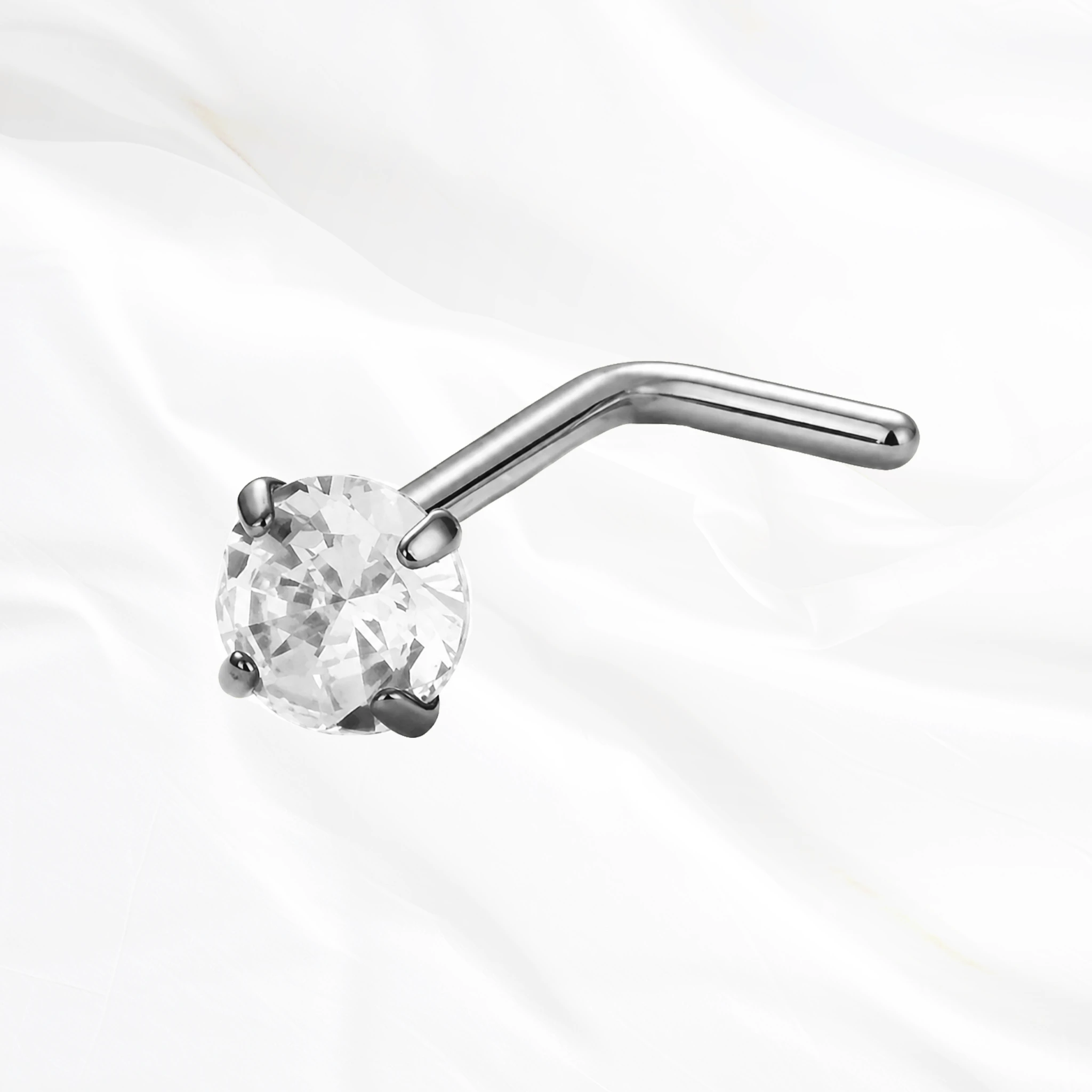 Piercing de nez en titane argenté Le Serti, tige coudée en L surmontée d’un zircon tenu par quatre griffes qui le surélèvent