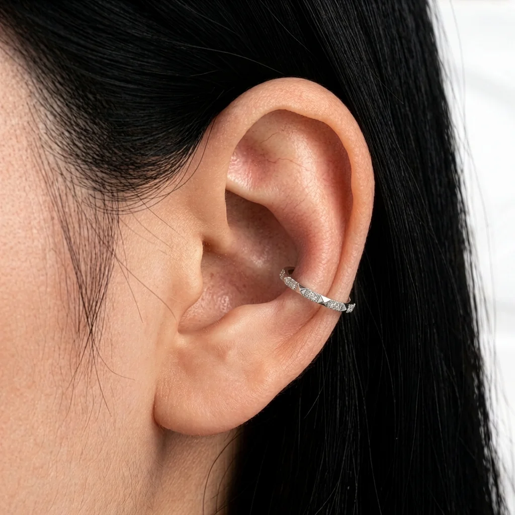 Piercing Le Damier en titane argenté porté au cartilage de l'oreille, anneau alternant pyramides polies et zircons pavés