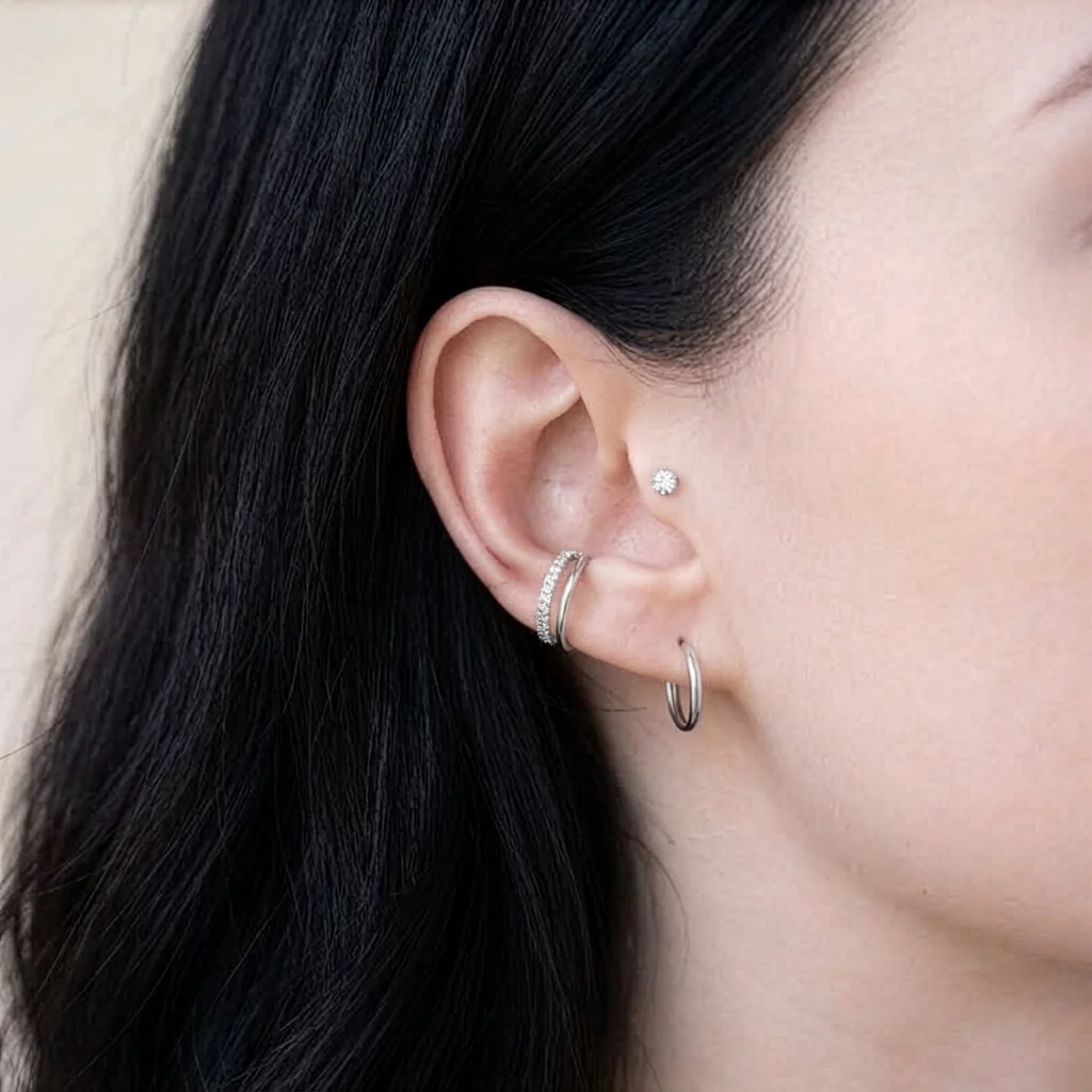 Piercing Le Serti Simple en titane argenté porté au tragus, petit zircon rond serti griffes dans une composition d'anneaux