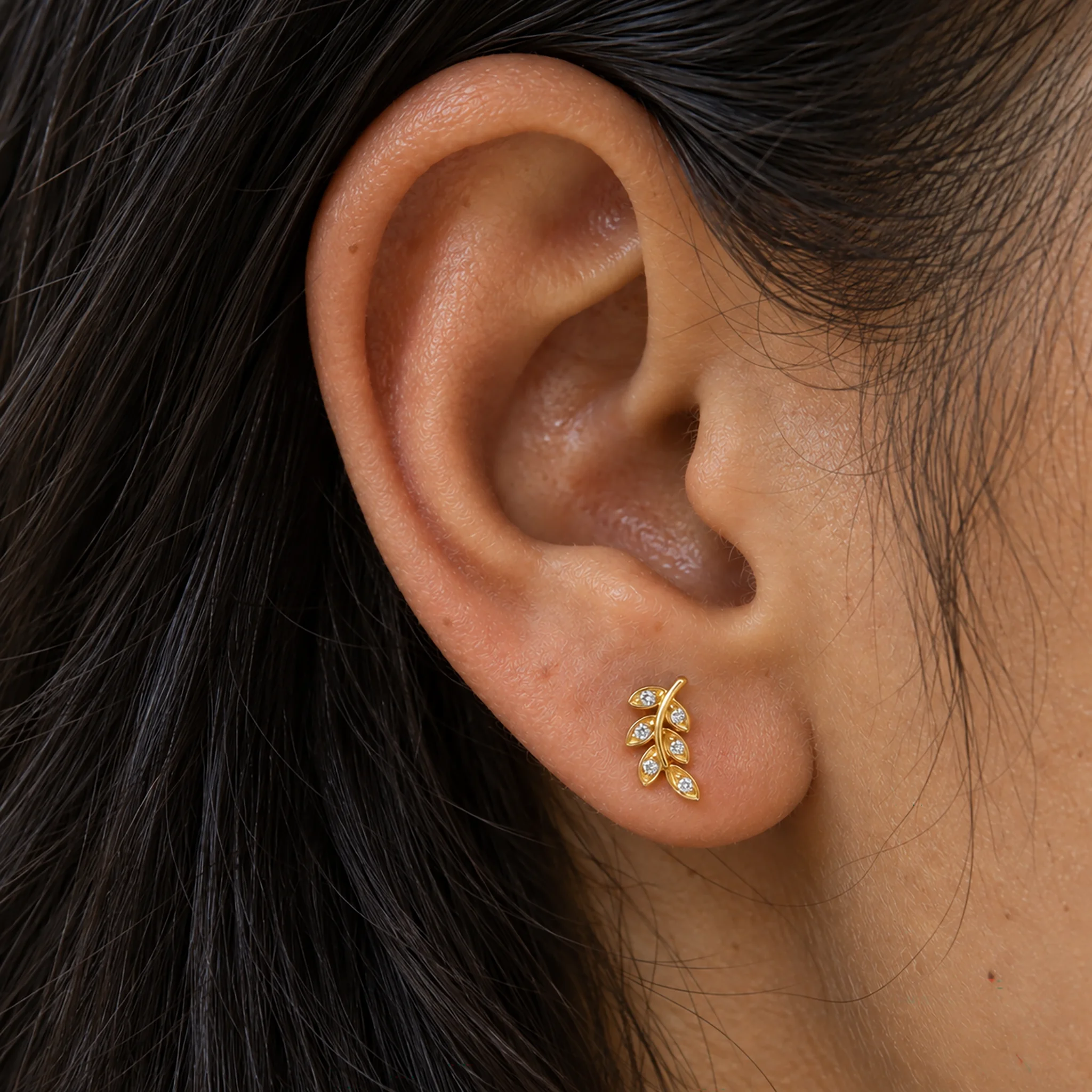 Piercing de lobe en titane doré L'Herbe Sauvage porté, brin de feuilles serties de zircons