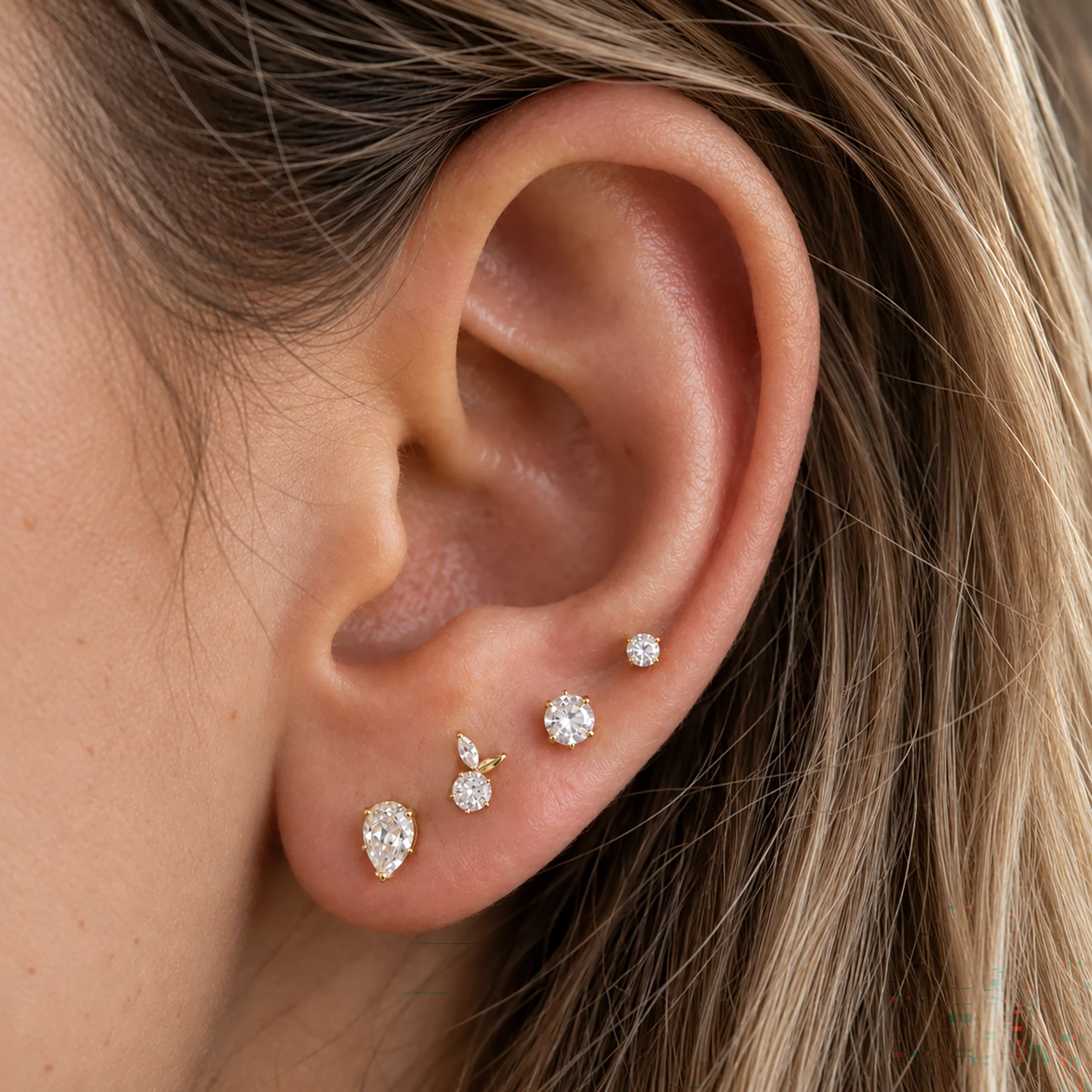 Piercing de lobe en titane doré Le Petit fruit porté, zircon rond et feuille marquise, avec d'autres puces dorées sur le lobe