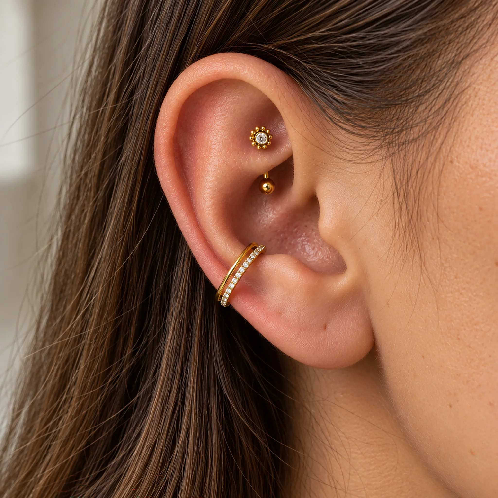 Piercing de rook en titane doré Le Tournesol porté dans le repli du haut de l'oreille, banane surmontée d'une fleur de tournesol, avec d'autres bijoux sur l'oreille